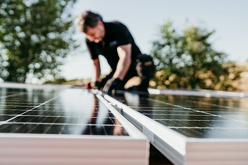 An installer mounts modules of an outdoor photovoltaic system.